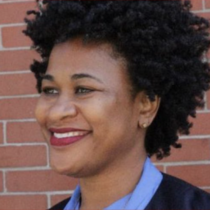 Tonia Spence, a smiling Black woman looking off to the side with short curly dark hair